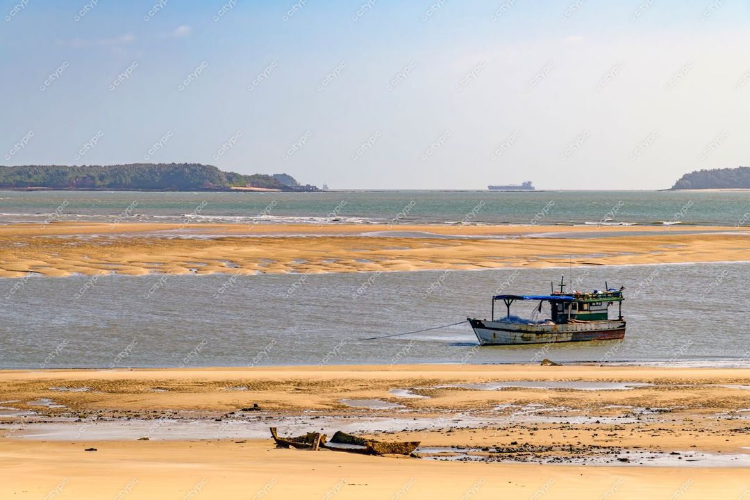 São Luís, Maranhão, barco pesqueiro ancorado em águas rasas com formações rochosas e navio de carga ao fundo