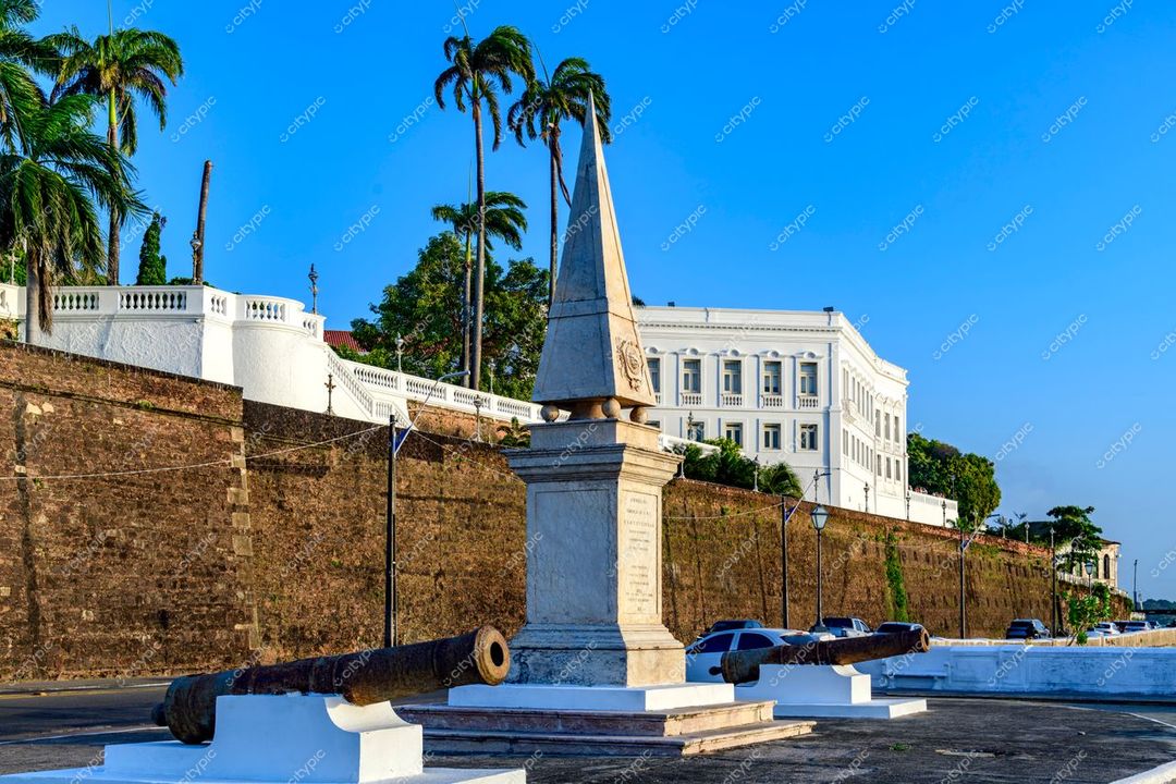 São Luís, Maranhão, obelisco central com canhões de ferro e edifício colonial sob céu azul e palmeiras