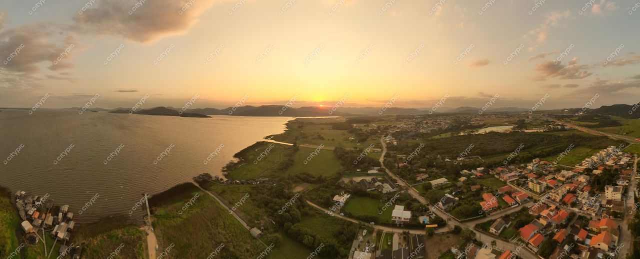 Lagoa do Mirim em Imbituba com pôr do sol, casas coloridas no primeiro plano e montanhas ao fundo