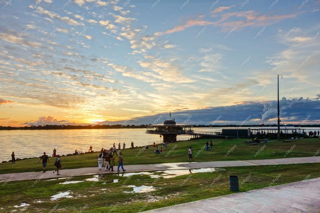 Porto Alegre, Rio Grande do Sul, pôr do sol sobre o Guaíba com gramado verde e estrutura flutuante ao fundo