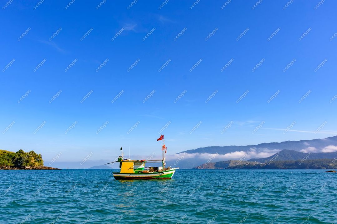 Ilhabela, São Paulo, barco de madeira colorido em águas calmas com montanhas e névoa ao fundo sob céu azul