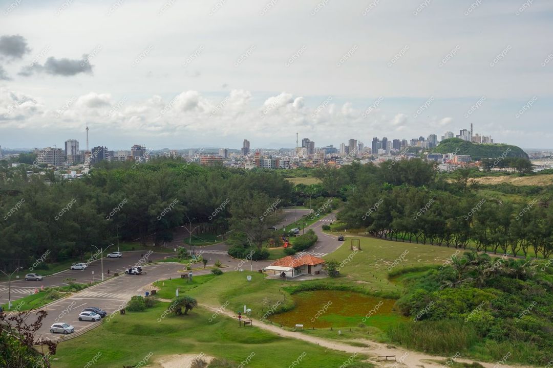 Torres, Rio Grande do Sul, vista panorâmica com vegetação densa, lago e prédios modernos sob céu nublado