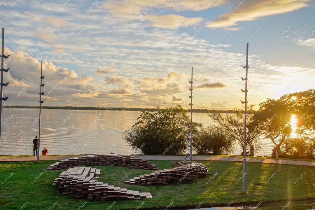 Porto Alegre, Rio Grande do Sul, pôr do sol no Guaíba com escultura circular e pessoas em ambiente urbano tranquilo