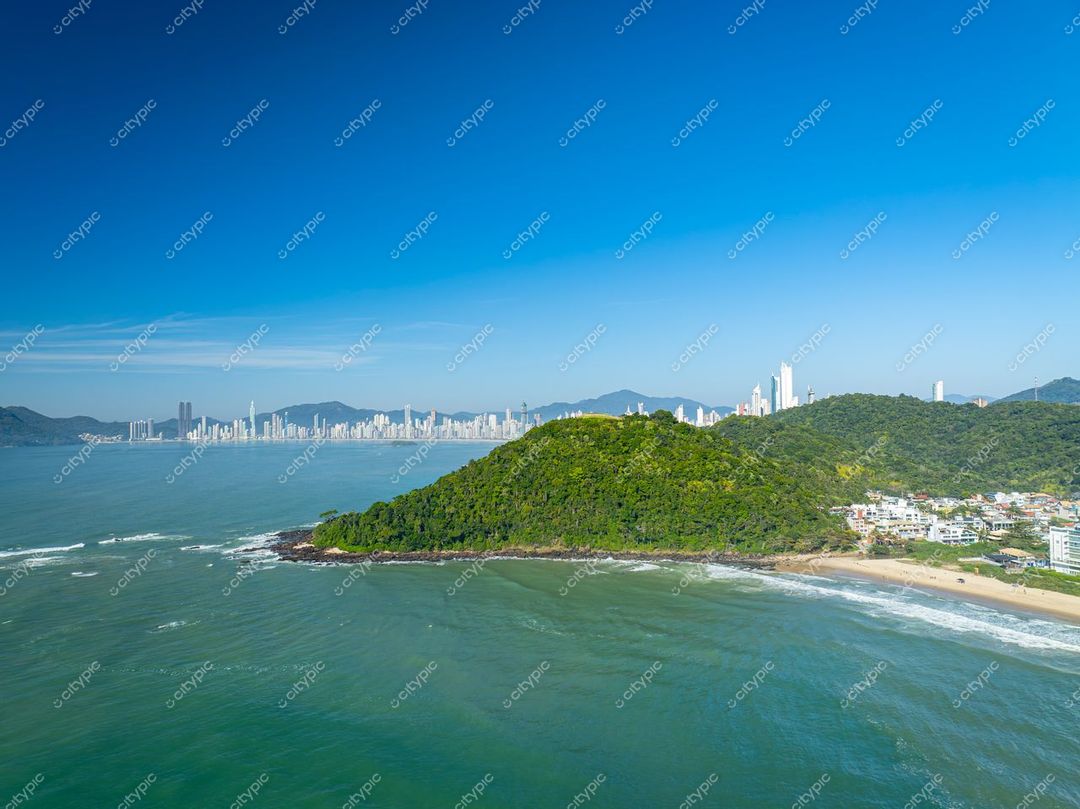 Itajaí, Santa Catarina vista aérea com montanhas verdes e edifícios altos sob céu ensolarado e mar calmo