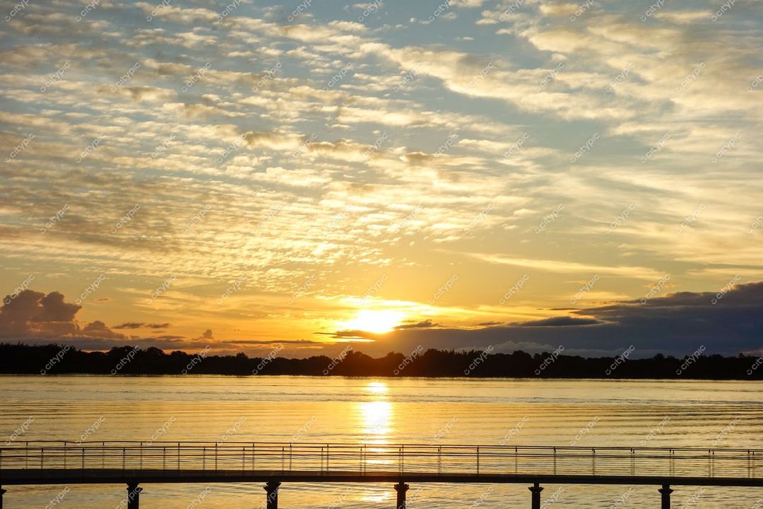 Porto Alegre, Rio Grande do Sul, pôr do sol sobre o Lago Guaíba com passarela de madeira e vegetação ao fundo