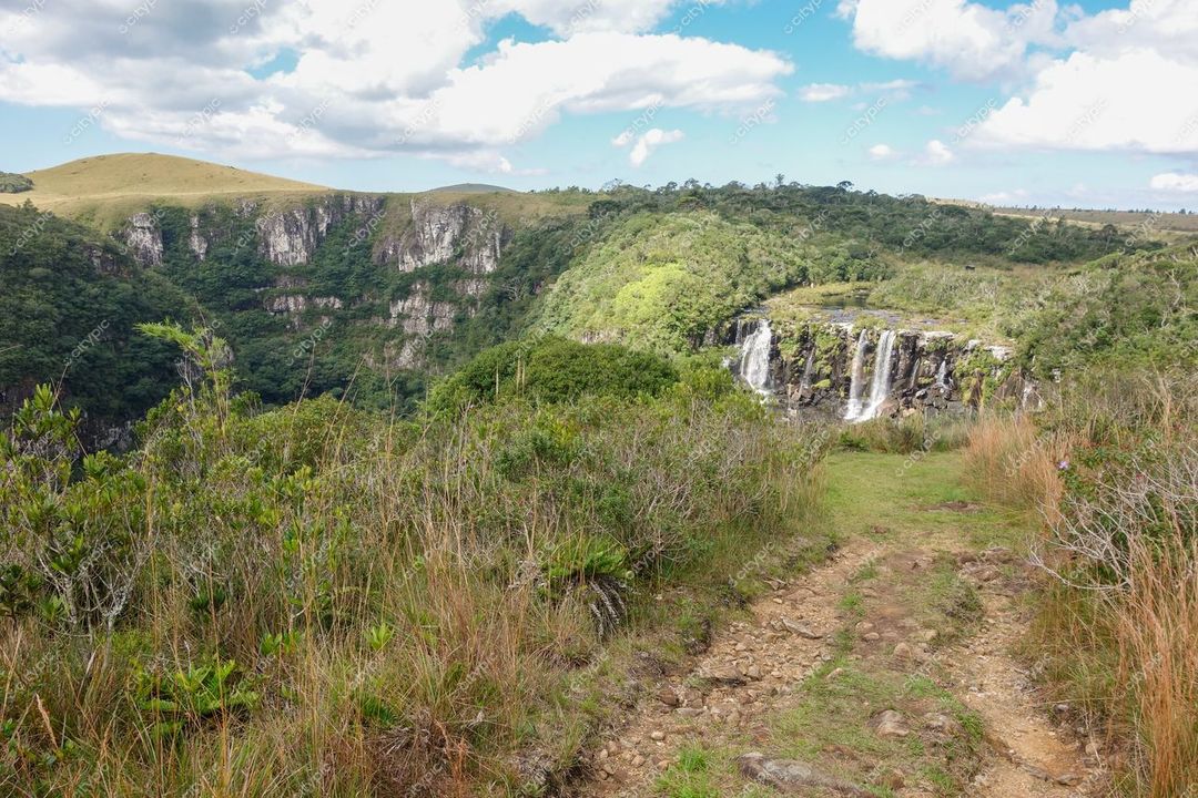 Cambará do Sul, Rio Grande do Sul, queda d’água em relevo íngreme com vegetação verdejante e céu parcialmente nublado