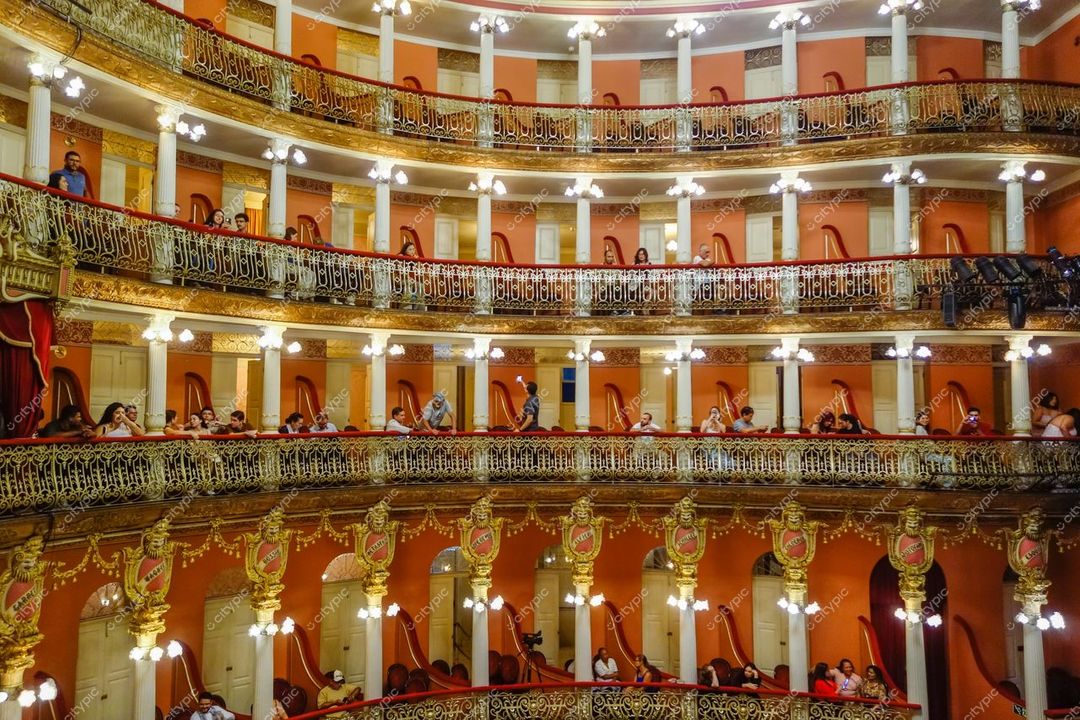Manaus, Amazonas, interior do Teatro Amazonas com assentos ornamentados em dourado e vermelho sob iluminação de lustres brilhantes