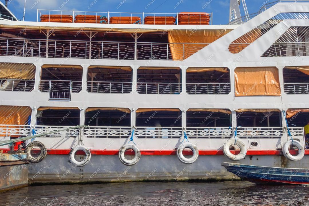 Manaus, Amazonas, barco de dois andares atracado em águas calmas com detalhes em vermelho e lonas laranjas