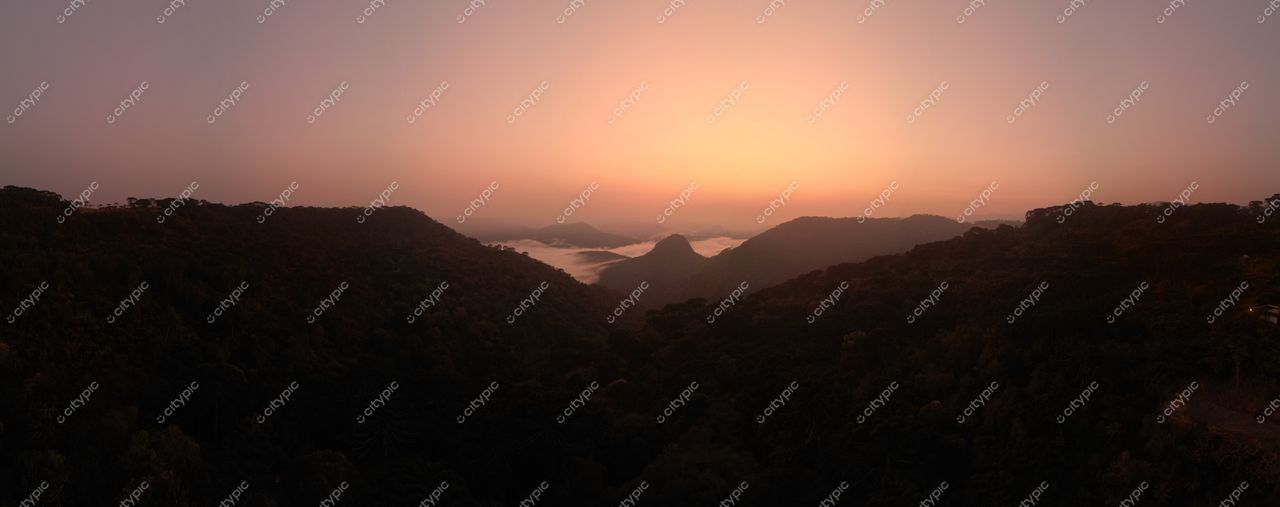 Morro da Igreja em Urubici com amanhecer iluminando montanhas e vegetação densa sob nuvens baixas no vale
